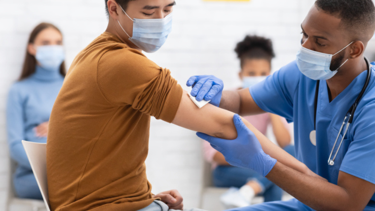 Photo of a man being given a vaccination by a male healthcare professional