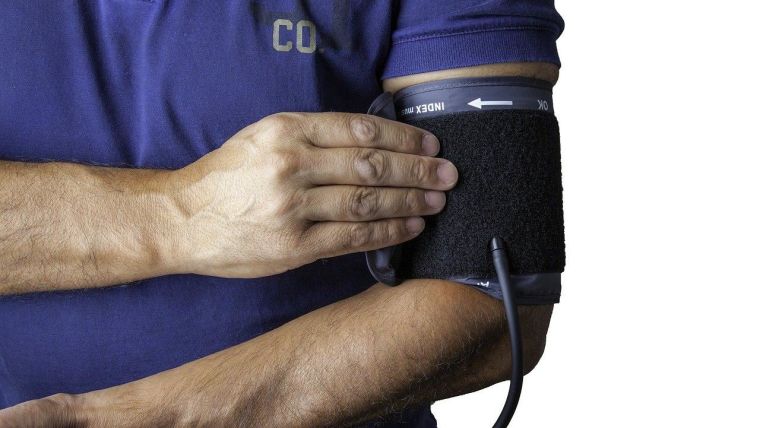 A man taking his blood pressure using a blood pressure cuff