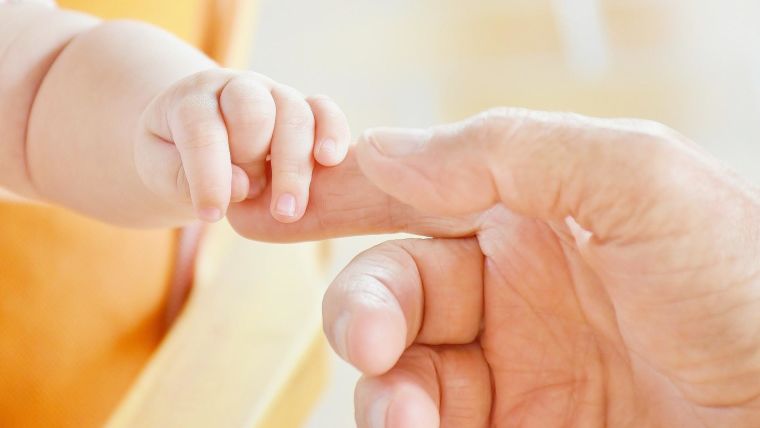 A baby's hand clutching a man's finger.