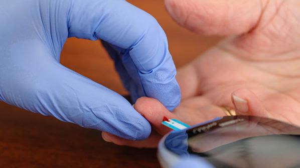 Close up of a patient receiving a finger prick blood glucose test