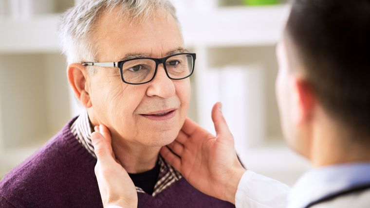Image of a male doctor examining and older man's throat